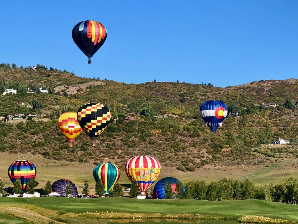 Colorful hot-air balloons flying over the Aspen landscape during a summer festival