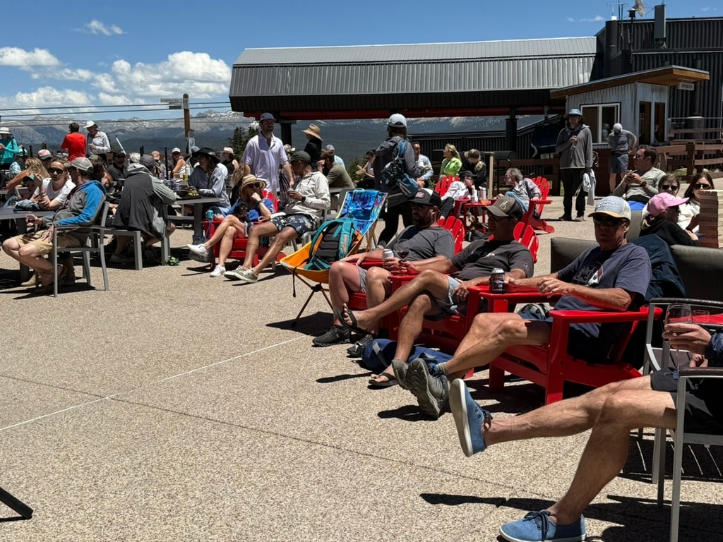 People relaxing in red chairs on an Aspen Mountain deck with mountain views