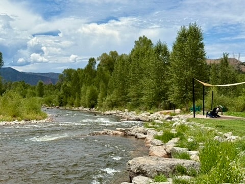 River with trees, rocks, and a hammock beside the water
